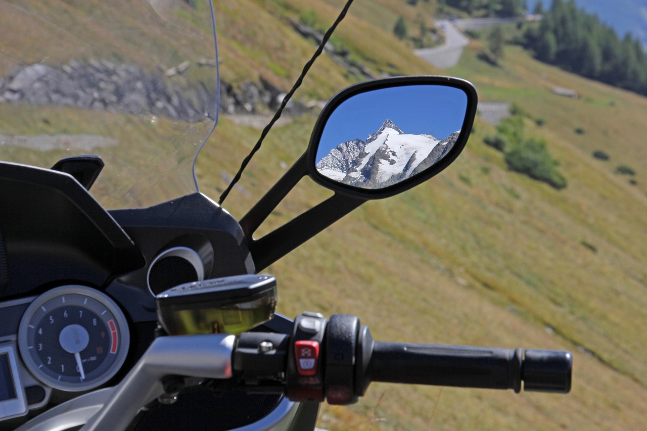noleggio moto lugano cruscotto di una moto con montagna innevata riflessa nello specchietto